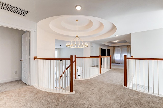 hall featuring an inviting chandelier, carpet, visible vents, and a tray ceiling