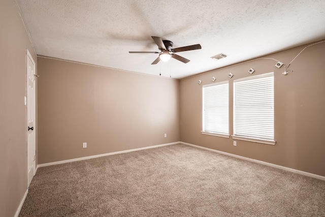 carpeted spare room featuring ceiling fan, a textured ceiling, visible vents, and baseboards