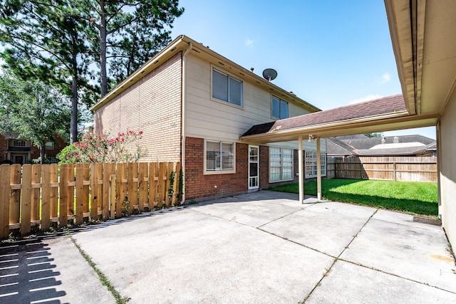 rear view of property with a yard, a patio area, brick siding, and fence