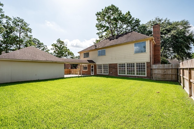 back of property featuring brick siding, a lawn, a chimney, and a fenced backyard