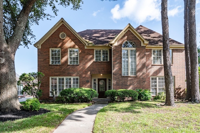 view of front of house featuring brick siding and a front yard