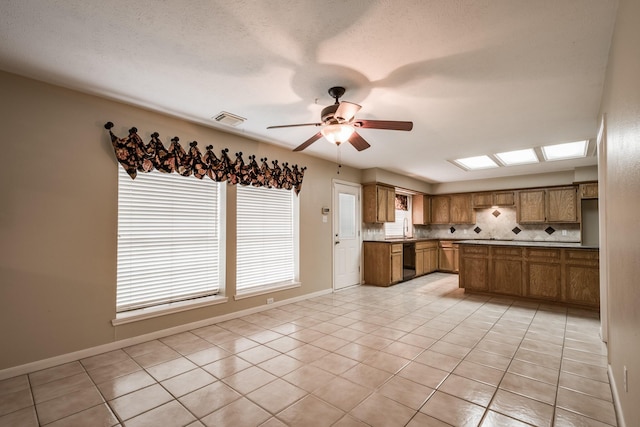 kitchen with light tile patterned floors, black dishwasher, visible vents, brown cabinets, and backsplash