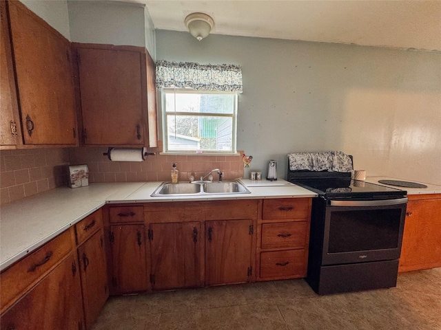 kitchen featuring brown cabinetry, electric stove, decorative backsplash, light countertops, and a sink