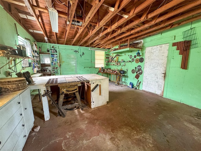 misc room with unfinished concrete flooring and a workshop area