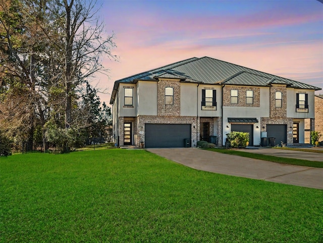 view of front of house featuring stucco siding, a front yard, metal roof, a garage, and driveway