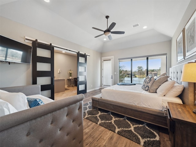 bedroom with a barn door, visible vents, lofted ceiling, wood finished floors, and access to exterior