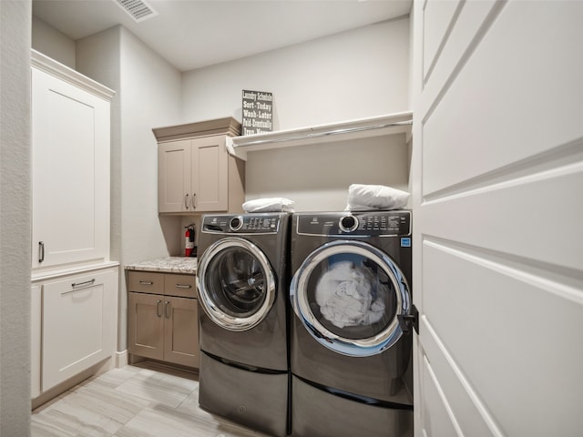 washroom featuring visible vents, washing machine and clothes dryer, and cabinet space