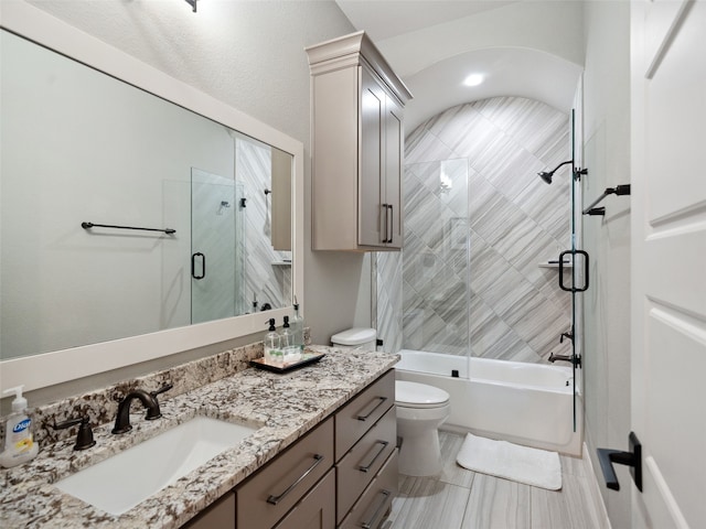 bathroom with shower / bath combination with glass door, vanity, and toilet