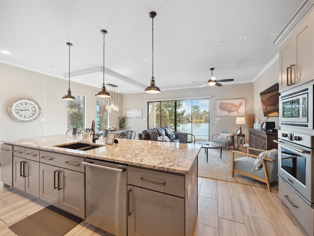 kitchen featuring an island with sink, appliances with stainless steel finishes, gray cabinets, crown molding, and a sink