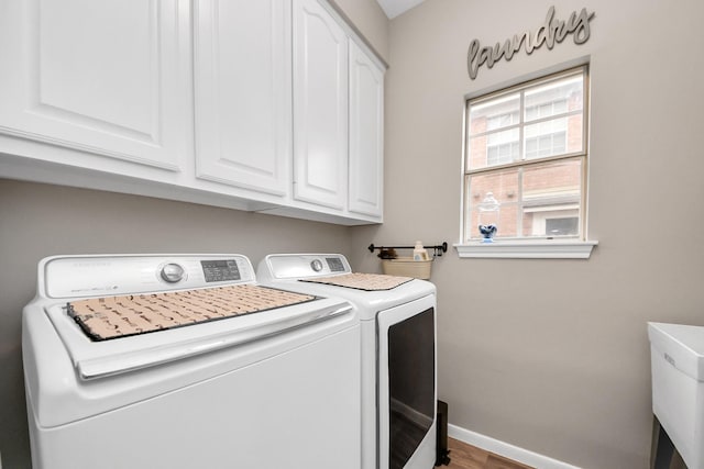 laundry area with independent washer and dryer, cabinet space, and baseboards