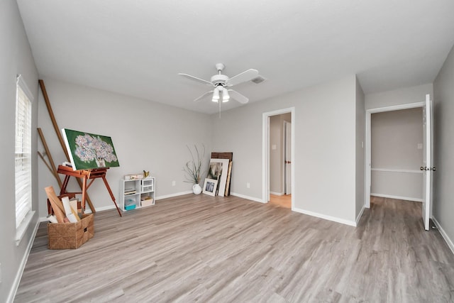 interior space with baseboards, ceiling fan, visible vents, and light wood-style floors