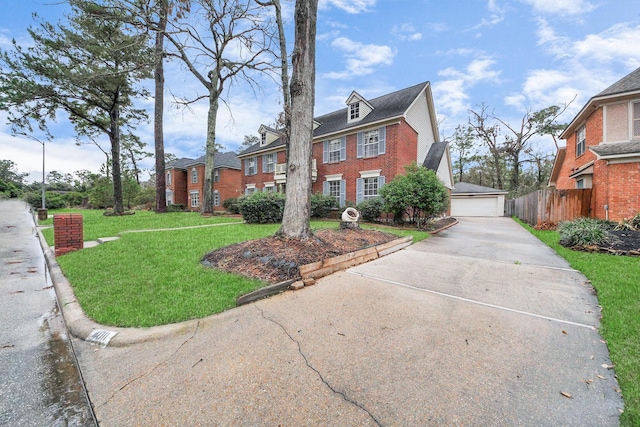 view of front of home with brick siding, fence, a garage, an outdoor structure, and a front lawn