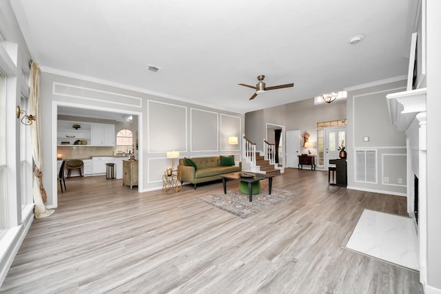 living room featuring light wood-style floors, visible vents, a decorative wall, and a premium fireplace