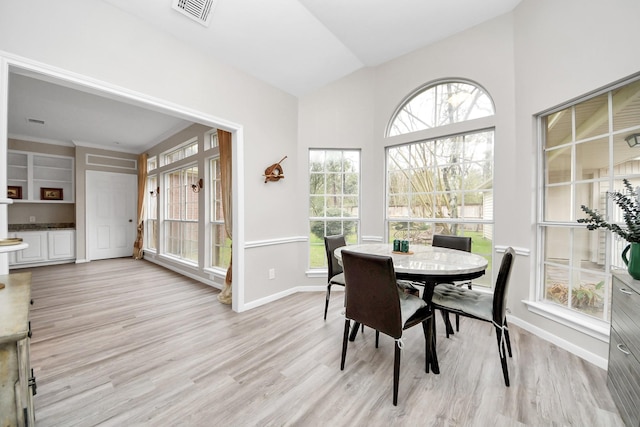 dining space featuring vaulted ceiling, light wood-type flooring, visible vents, and baseboards