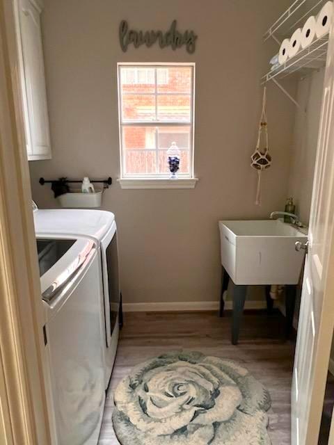 laundry area with a sink, light wood-style floors, washing machine and clothes dryer, and baseboards