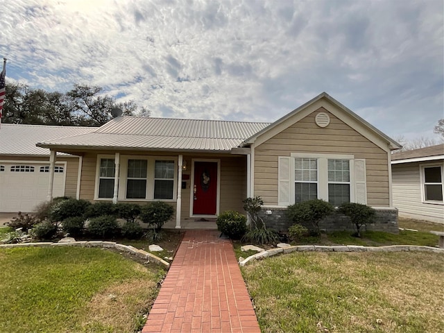 single story home featuring a garage, metal roof, and a front lawn