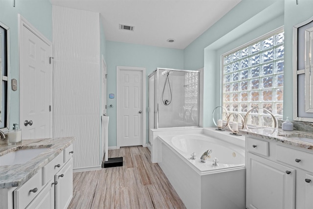 full bathroom with a stall shower, visible vents, two vanities, and a sink