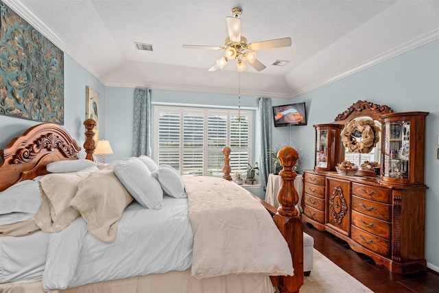 bedroom featuring dark wood-style floors, a raised ceiling, visible vents, and crown molding