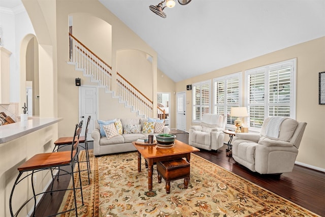 living room with baseboards, arched walkways, wood finished floors, stairs, and high vaulted ceiling