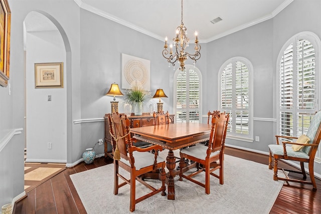 dining area featuring arched walkways, visible vents, crown molding, and hardwood / wood-style floors