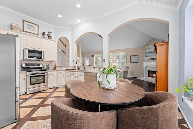 kitchen featuring recessed lighting, decorative backsplash, appliances with stainless steel finishes, ornamental molding, and vaulted ceiling