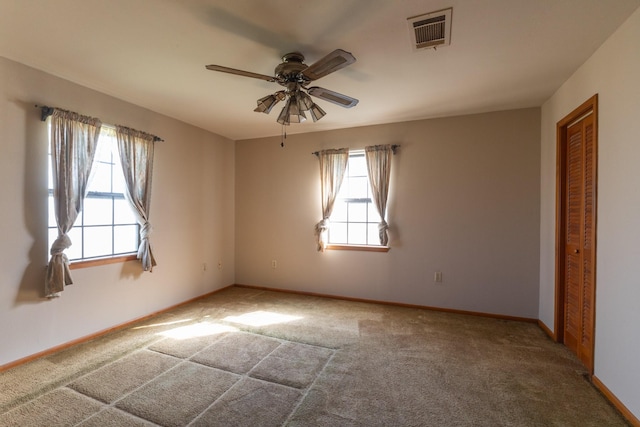 spare room with carpet floors, visible vents, ceiling fan, and baseboards