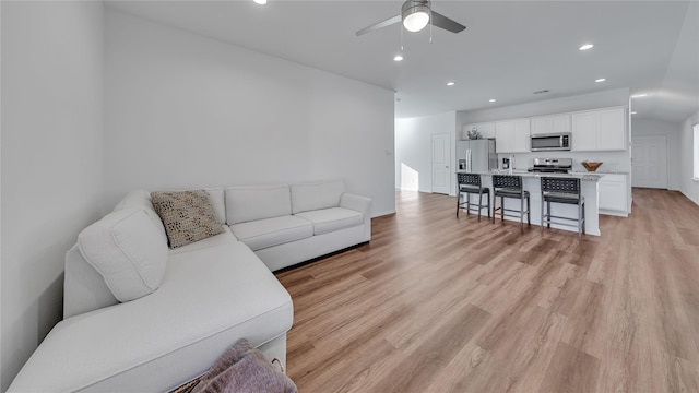 living room with light wood-type flooring, ceiling fan, baseboards, and recessed lighting