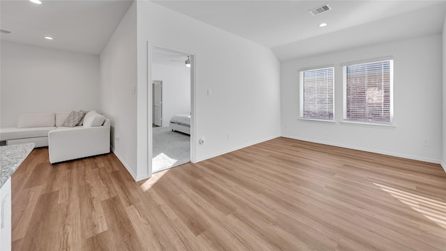 unfurnished living room with light wood finished floors, baseboards, visible vents, vaulted ceiling, and recessed lighting