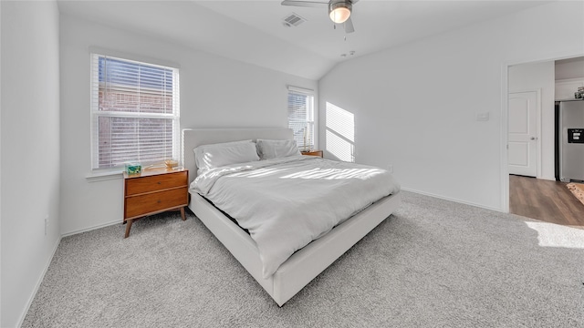 carpeted bedroom featuring lofted ceiling, stainless steel fridge with ice dispenser, visible vents, ceiling fan, and baseboards