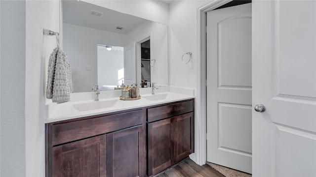 bathroom with double vanity, visible vents, a sink, and wood finished floors