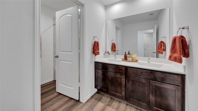 bathroom with double vanity, a sink, and wood finished floors