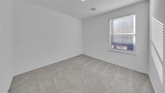 spare room featuring carpet, visible vents, and baseboards