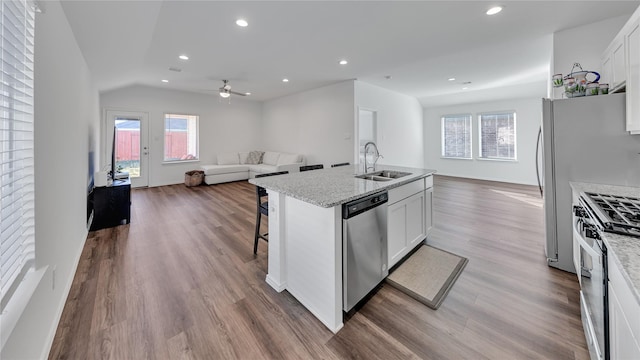 kitchen with white cabinets, dark wood-style floors, appliances with stainless steel finishes, open floor plan, and a sink