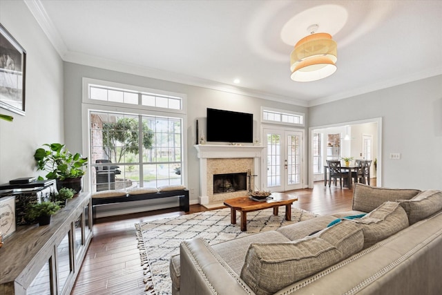 living area featuring french doors, a fireplace, hardwood / wood-style flooring, and crown molding