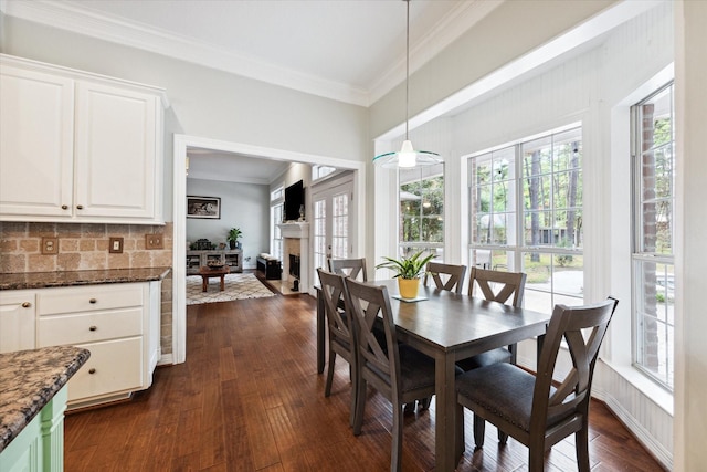 dining space featuring a fireplace, ornamental molding, and dark wood-type flooring