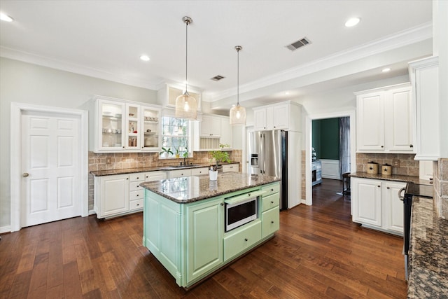 kitchen with green cabinetry, a sink, visible vents, and white cabinetry