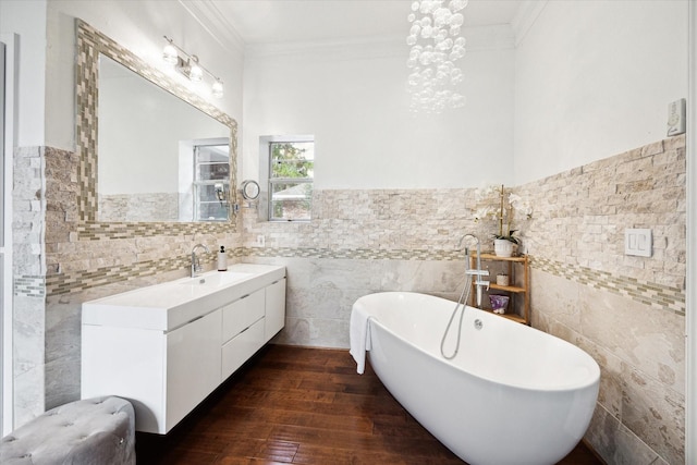 full bath with a freestanding tub, wood finished floors, vanity, tile walls, and ornamental molding