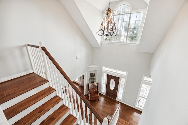 foyer with stairs, high vaulted ceiling, wood finished floors, and a healthy amount of sunlight