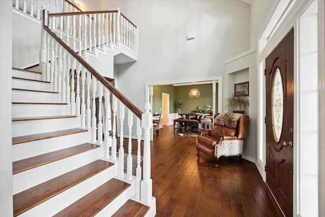 foyer entrance featuring stairway, baseboards, a towering ceiling, and hardwood / wood-style floors