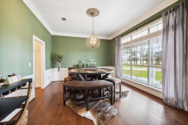 dining area with a notable chandelier, a wainscoted wall, visible vents, dark wood finished floors, and crown molding