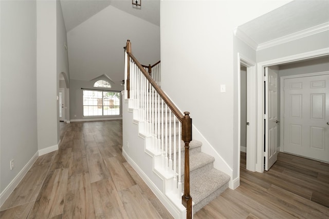 stairway featuring crown molding, baseboards, arched walkways, and wood finished floors