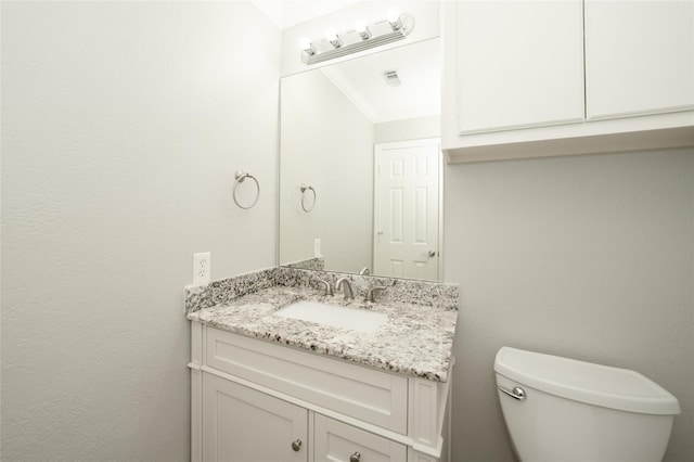 half bath with visible vents, vanity, and toilet