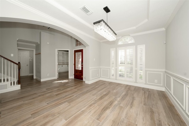 empty room with visible vents, stairs, arched walkways, and a decorative wall