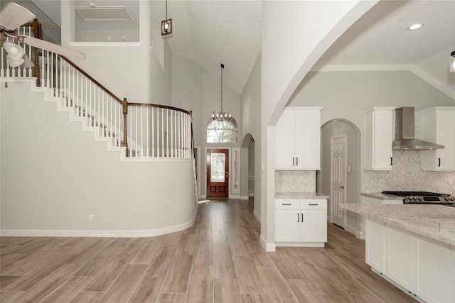 foyer with light wood-style floors, baseboards, and high vaulted ceiling