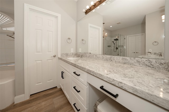 bathroom featuring a washtub, a stall shower, wood finished floors, and vanity