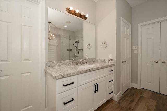 full bath featuring visible vents, a stall shower, vanity, wood finished floors, and baseboards