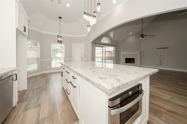 kitchen with light stone counters, appliances with stainless steel finishes, a fireplace, and light wood-style flooring