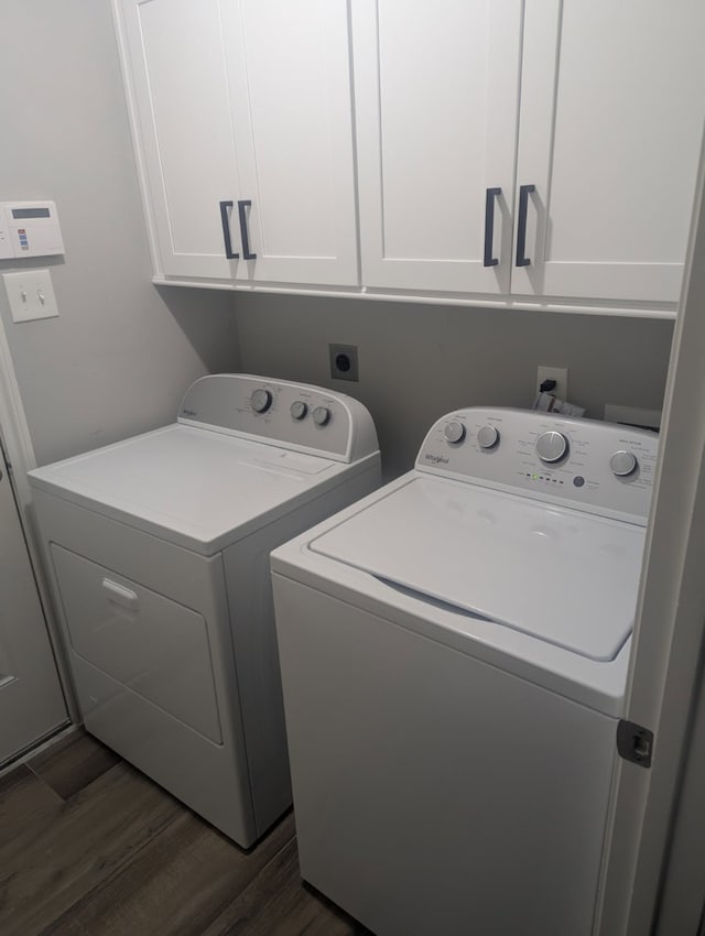 clothes washing area with dark wood-type flooring, washing machine and clothes dryer, and cabinet space