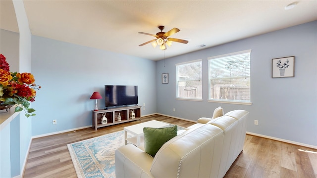 living room with ceiling fan, light wood-type flooring, visible vents, and baseboards