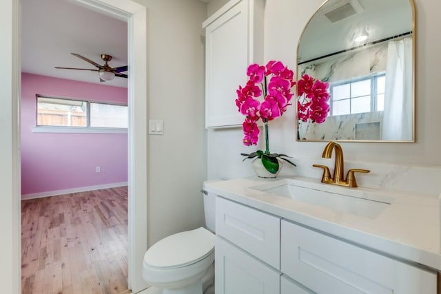 bathroom with visible vents, toilet, ceiling fan, vanity, and wood finished floors